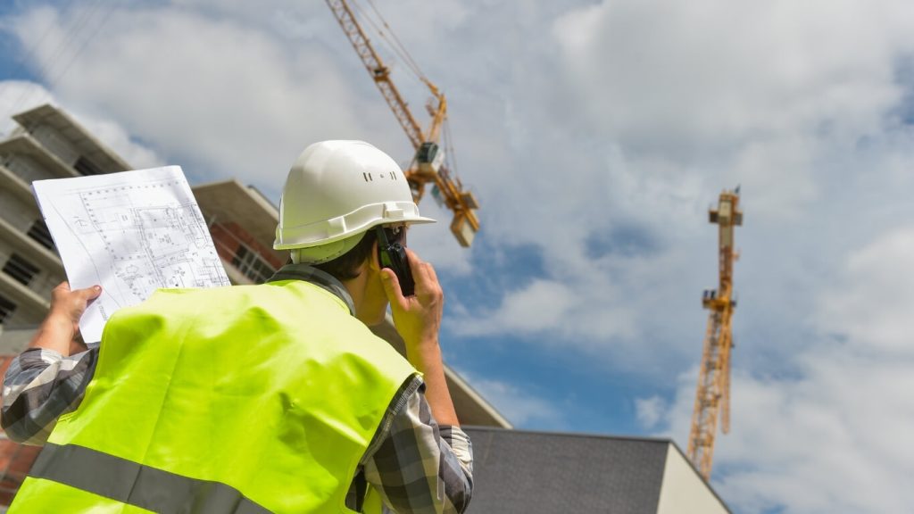 Công nhân đang cầm máy bộ đàm liên hệ nhân viên trên cẩu